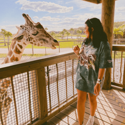 Woman smiling and taking a photo with a giraffe up close at Wild Florida Adventure Park.