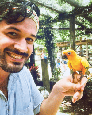 Man poses with a little yellow bird in the Bird Aviary at Wild Florida